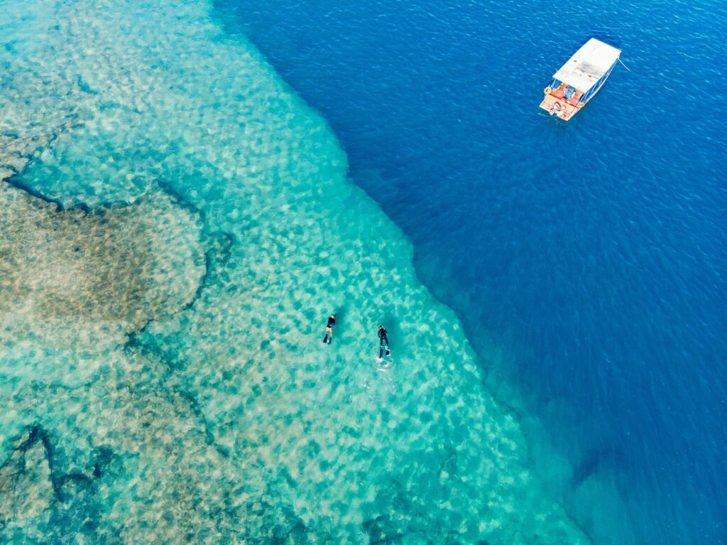 Aerial shot of snorkelers and a boat over vibrant, clear waters in Brazil.